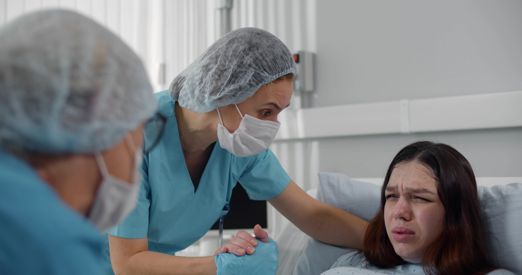 Doctor and nurse helping young pregnant woman in labor.